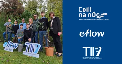 The image shows a group of people including some school students and teachers standing in a green outdoor space. Two sign boards are held by the group which are logos of eFlow and TII