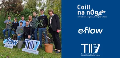 The image shows a group of people including some school students and teachers standing in a green outdoor space. Two sign boards are held by the group which are logos of eFlow and TII